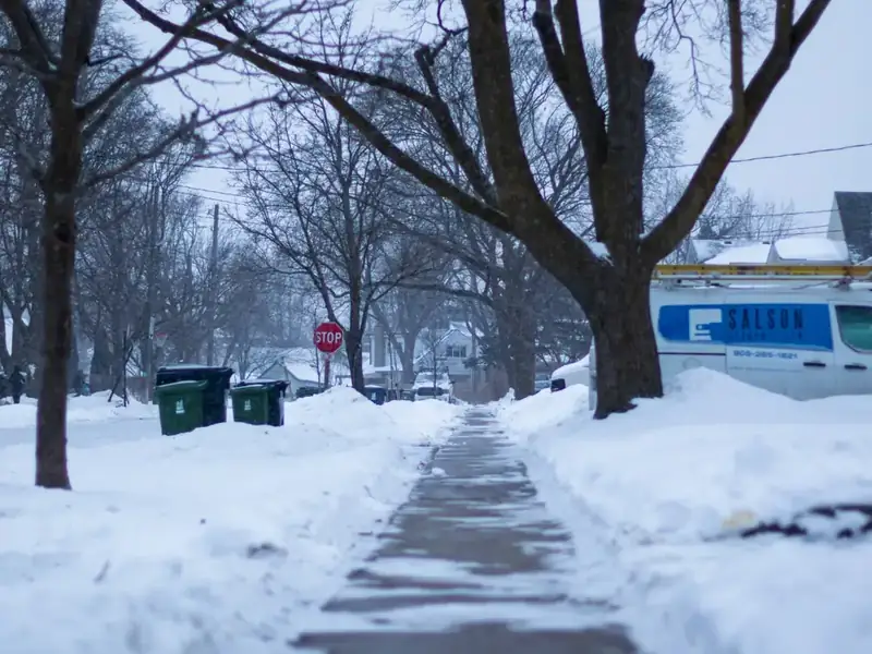 A snow-covered residential sidewalk in winter