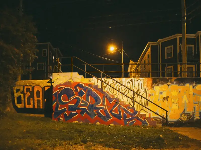A wall covered in colourful graffiti at night