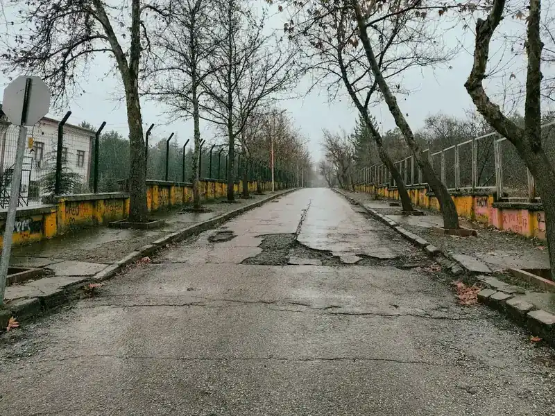 A city street with cracked and broken asphalt